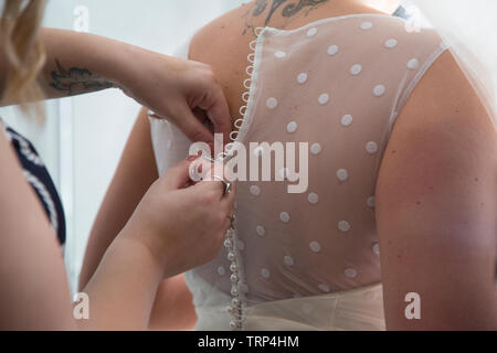 Wedding dress being done up on a Brides wedding day, close up of wedding dress being done up before the ceremony Stock Photo