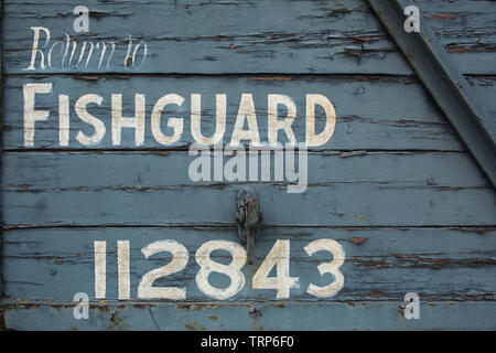 'Return to Fishguard 112843' marking painted on wooden side of Great Western Railways Mink G 20Ton covered van / goods wagon at Didcot Railway Centre. Stock Photo