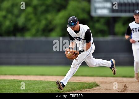 Second baseman charging a soft hit ground ball before throwing on to first bast to retire the batter. USA. Stock Photo