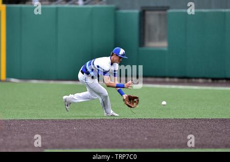 Second baseman ranging far to his left to field a ground ball on the outfield turf before throwing the batter out at first. USA. Stock Photo