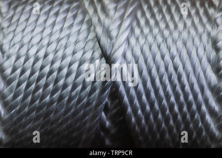 A macro of a spool of string wound in a very symmetrical pattern on a tube.  The image is in very sharp focus and has a high contrast. Stock Photo
