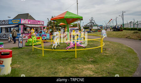 Food stalls, amusements, fairground rides and entertainment in one of the pleasure parks along the Golden Mile in the coastal town of Great Yarmouth, Stock Photo