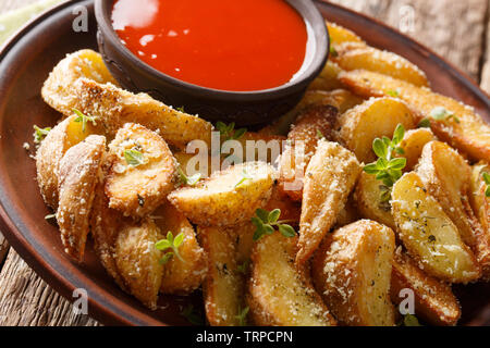 Baked potato wedges with parmesan and oregano, served with pepper sauce close-up on a plate on the table. horizontal Stock Photo