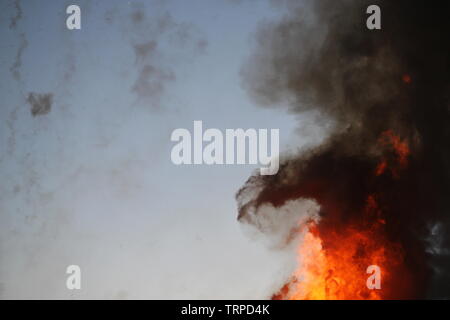 Flames and black smoke rising against the sky Stock Photo