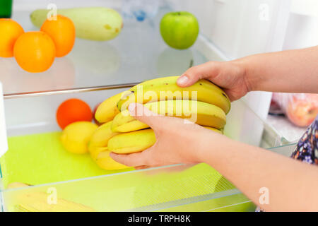 Woman getting bananas from fridge. Close up. Stock Photo