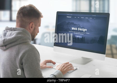 Web design studio concept with man and computer display with modern web site presentation. Stock Photo