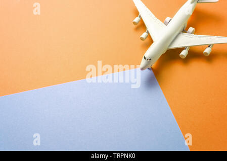 Passenger jet airplane, minimal concept, on orange and blue colors paper with geometric shapes. Minimal transportation, travel or vacation concept. Stock Photo