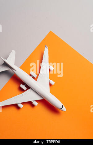 Passenger jet airplane, minimal concept, on orange and white colors paper with geometric shapes. Minimal transportation, travel or vacation concept. Stock Photo