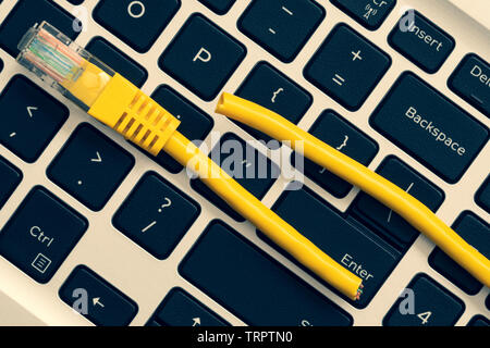 Concept of internet censorship and interruption.    Laptop keyboard with cut internet cable. Stock Photo