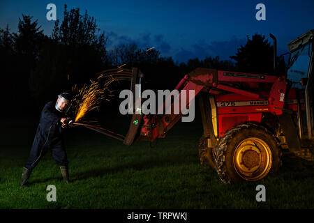 A farmer making repairs late into the night Stock Photo