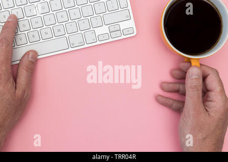 Man working on computer keyboard top view minimal office pink color background Stock Photo