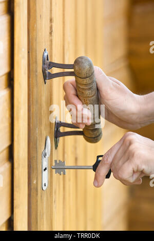 hand unlocking front door lock of house, closeup Stock Photo