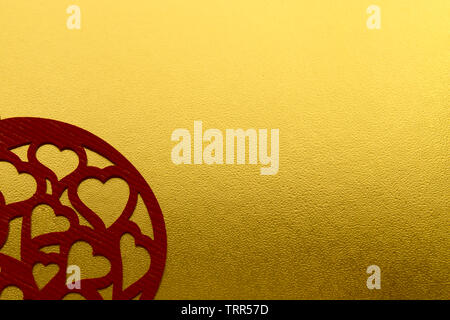 Shiny yellow metallic gold leaf foil texture background with carved red hearts. Love card Stock Photo