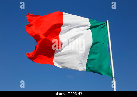 Close-up of the Italian national flag against a blue sky. Stock Photo