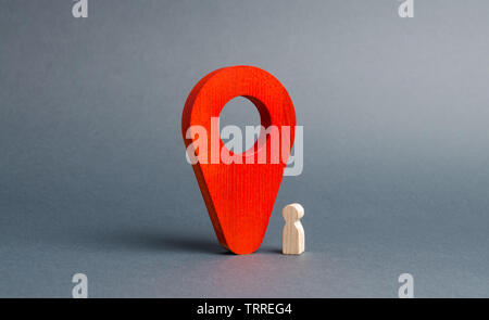 The wooden figurine of the child stands near a huge red pointer. tracking the location of the child in real time, parental control. Ensuring safety an Stock Photo