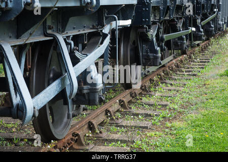Perspective view of railway train goods wagon carriage wheels, lever brakes and leaf suspension system on tracks at Didcot Railway Centre, Oxfordshire