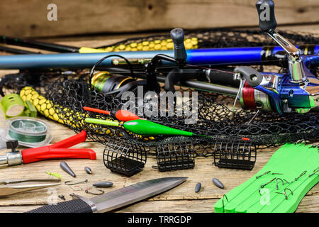 Fishing tackle. Fishing rods, floats, fishing rod holder, knife, fishhooks  and landing net on old wooden background Stock Photo - Alamy