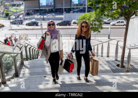 two beautiful girls with shopping bags walk up stairs in the heart of the city Stock Photo