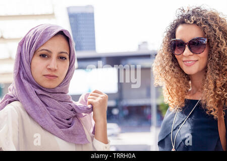 two beautiful girls with shopping bags walk up stairs in the heart of the city Stock Photo