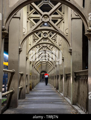A man stands on the path of repeating iron arches that supports the River Tyne's High Level Bridge between Newcastle and Gateshead. Stock Photo