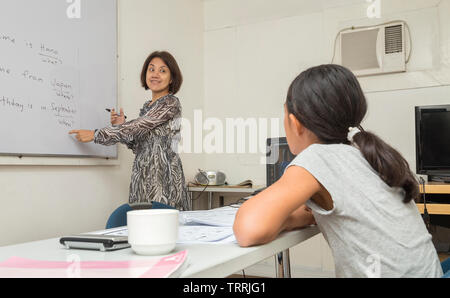 Manila, Philippines - August, 18, 2016: An English female teacher is writing and explaining the rules of English on the white board, teaching a girl Stock Photo