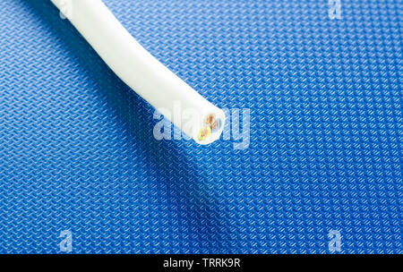 Cross-section of PVC cable on blue ribbed technological background Stock Photo