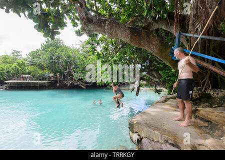 Young woman jumping into Blue Lagoon, a popular scenic turquoise swimming hole near Port Vila, Efate Island, Vanuatu, Melanesia Stock Photo