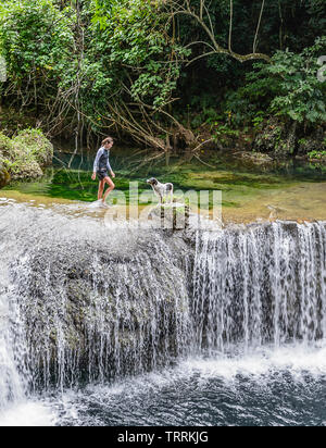 A young girl and a dog on top of a waterfall at Rarru Rentapao River near Port Vila, Efate Island, Vanuatu, Melanesia Stock Photo