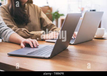 People using and looking at laptop computer on wooden table together Stock Photo