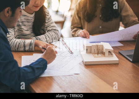 Group of an architect working and discussing about an architecture model together with shop drawing paper on table in office Stock Photo