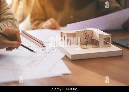 Group of an architect working and discussing about an architecture model together with shop drawing paper on table in office Stock Photo