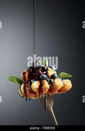 Homemade Belgian waffles with  chocolate syrup, blueberry and mint on a dark background. Copy space. Stock Photo