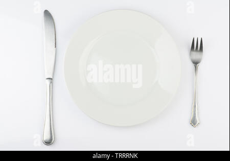 White plate with fork and knife above top view isolated Stock Photo