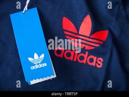 LONDON, UK - JUNE 05, 2019: Adidas Originals Label red color on blue fabric with shopping tag. Stock Photo