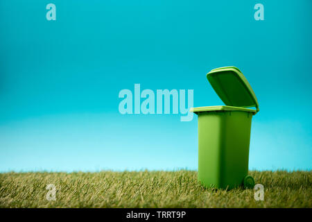 Green recycle bin on green grass and blue sky Stock Photo