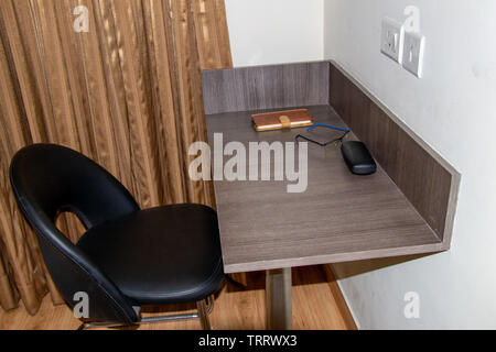 Wooden table or desk with a chair in a room, specs and diary on table Stock Photo