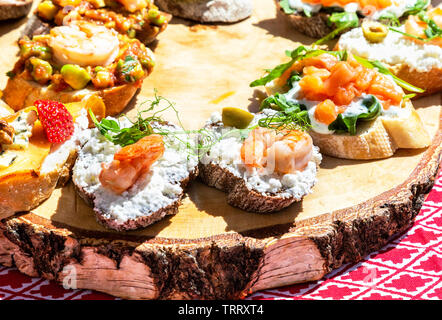 Tasty fresh sandwiches with different filling on wooden board Stock Photo