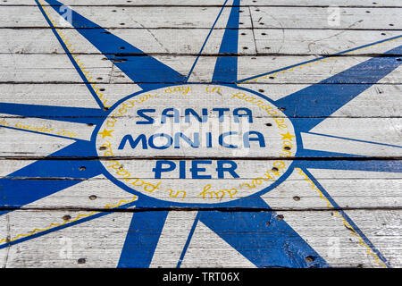 Sign on the ground says Santa Monica Pier, another day in paradise. The sign is located at the end of Santa Monica pier, in southern California. Stock Photo