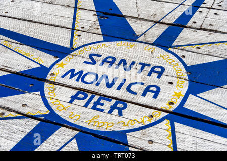 Sign on the ground says Santa Monica Pier, another day in paradise. The sign is located at the end of Santa Monica pier, in southern California. Stock Photo