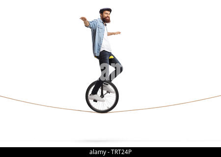Full length shot of a man riding a unicycle on a rope and balancing with his hands isolated on white background Stock Photo