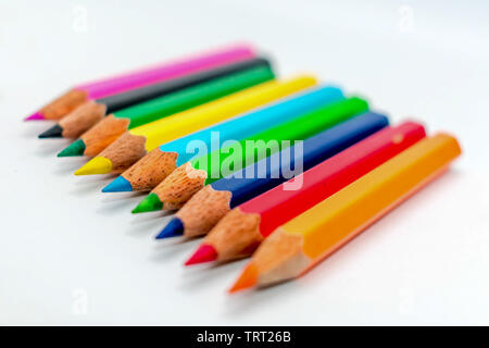 Multi colored bunch of assorted rainbow color pencil line up in a row close together side by side arranged in white background, flat lay. Selective fo Stock Photo