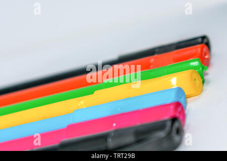 Standing Out From The Crowd Concept. Bunch of assorted multi colored boll point pens in rainbow arrangement on white background, flat lay. Geometry pa Stock Photo