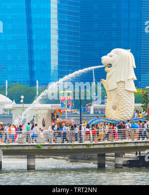 SINGAPORE - JANUARY 14, 2017: Crowd of tourists by Singapore Lion fountain, glass facades of skyscrapers in background Stock Photo