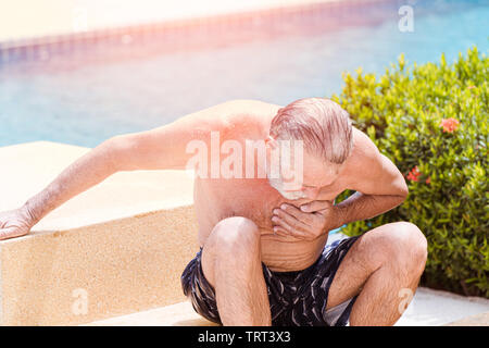 Elder pain suffer from heart attack at swimming pool in summer hot sunny day Stock Photo