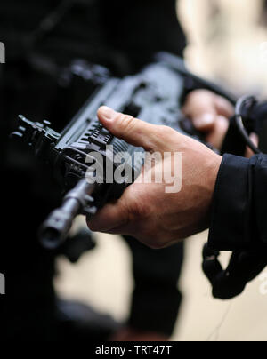 Details with the hands of a man holding an automatic rifle Stock Photo