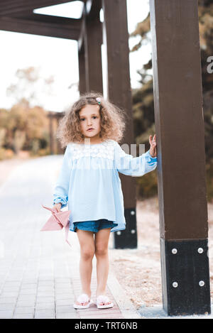 Stylish baby girl 3 4 year old wearing summer trendy clothes holding toy outdoors. Looking at camera Stock Photo Alamy