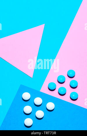 blue and white tablets laid out in the form of a triangle or an arrow on a paper background of blue and pink. Medication and prescription pills minima Stock Photo