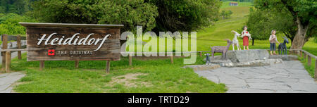 Maienfeld, GR / Switzerland - 9 June 2019: tourist attraction sign and wooden puppets of the fictional Heidi story in the Swiss Alps village of Maienf Stock Photo