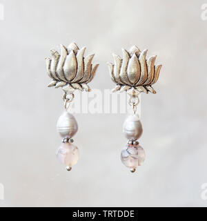 Mineral stone agate and pearl beads lotus shape earrings on neutral background Stock Photo