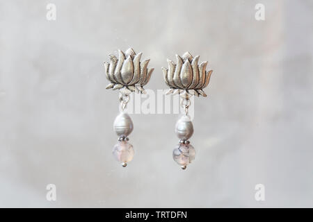 Mineral stone agate and pearl beads lotus shape earrings on neutral background Stock Photo
